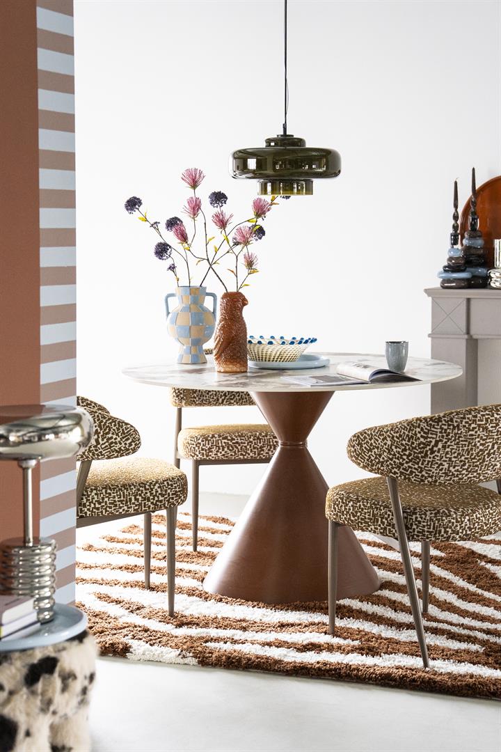 Ronde eettafel met een elegant tafelblad in marmerlook van gesinterde steen en een bruin, zandlopervormig metalen onderstel.